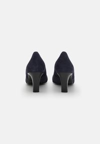 Mørkeblå semsket høyhælte sko med spiss tå-design og en middels svart avsmalnet hæl. Den glatte teksturen kompletterer den elegante silhuetten.