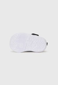 Chaussure de sport noire avec une tige texturée et une semelle en caoutchouc blanche dotée d'un motif pour l'adhérence et la traction.