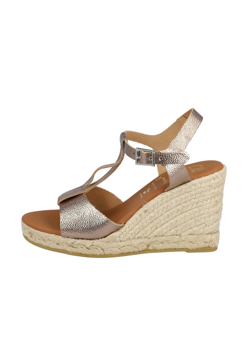 Sandalias de cuña con un upper texturizado metálico, correa ajustable en el tobillo y una suela cubierta de cuerda natural. La plantilla marrón complementa el diseño.