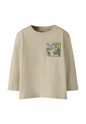Beige long-sleeve t-shirt with a crew neck. Features a pocket graphic of dinosaurs and the text "WHAT'S UP!" in blue, green, and yellow.