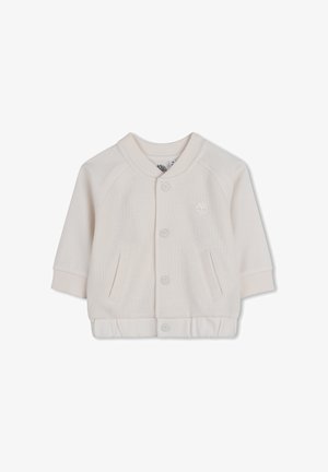 Lichtbeige jas met een gestructureerde stof, geribde kraag en manchetten, knoopsluiting aan de voorkant en twee zijzakken. Heeft een klein logo op de borst.