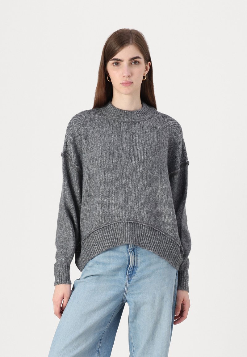 Grå strikket genser med rund hals, nedfalte skuldre og ribbede mansjetter, kombinert med lyseblå, løs passform jeans.