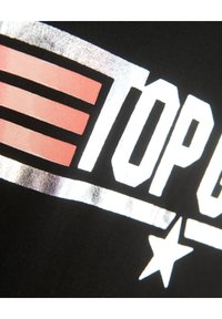 Mustat kangas, jossa on rohkeaa metallinhohtoista hopeaa ja pinkkiä graafista tekstiä raitojen ja tähden yksityiskohtien kanssa, korostaen kontrastia ja tekstuuria.