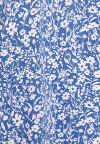 Tejido azul con un patrón floral blanco que presenta diversas flores y hojas, diseñadas de manera intrincada y dispuestas densamente. Textura suave.