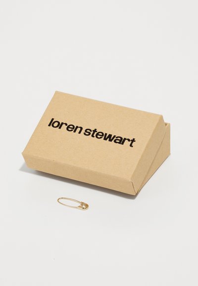 Kultakotelo, jossa on pieni kirkas jalokivi, asetettu ruskean pahvilaatikon viereen, jossa on mustalla painettu teksti "loren stewart."