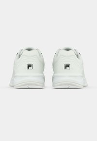 Egy pár fehér sportcipő fekete FILA logóval a sarkán, hátulról nézve, fehér háttér előtt.