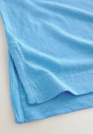 Tissu en coton bleu avec une texture douce, plié à l'ourlet, présentant des bords cousus et un léger éclat.