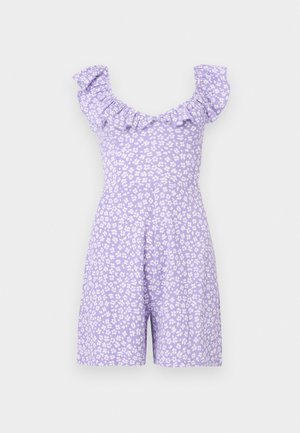 Λιλά αμάνικη ολόσωμη φόρμα με λευκό φλοράλ σχέδιο και βολάν στο ντεκολτέ σε απλό ανοιχτό φόντο.