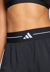 Black athletic shorts with an elastic waistband featuring a white adidas logo and stripe detail. Lightweight fabric with a smooth texture.