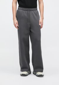 Szare spodnie dresowe o szerokich nogawkach, z elastycznym pasem i sznurkiem do regulacji. Wykonane z miękkiego materiału, z bocznymi kieszeniami i gładką fakturą.