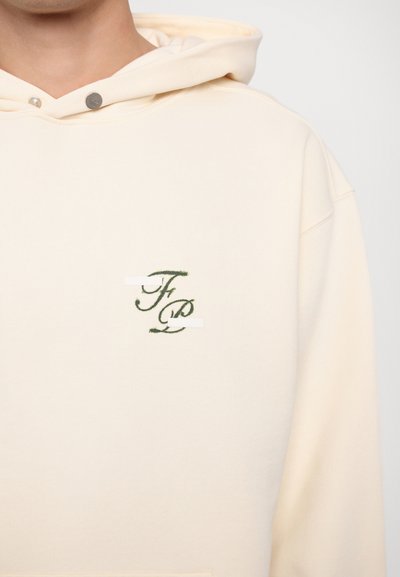 Cream hoodie with drawstring, soft texture, features green embroidered initials "F" and "P" on the chest. Silver hardware on the neckline.