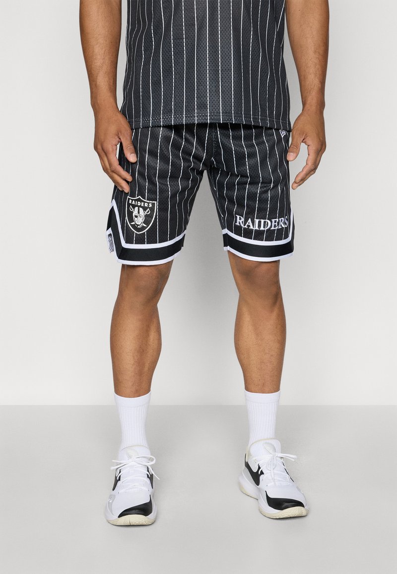 Black mesh sports shorts feature vertical white stripes, a Raiders logo on the left leg, and white trim at the hem. Paired with white socks and sneakers.