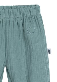 Groene textuurbroek met een elastische tailleband. Opvallend geborduurd wolkendetail aan de voorkant en een klein label aan de zijkant.