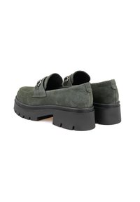 Grüne Wildleder-Loafer mit einer dicken schwarzen Gummisohle, ausgestattet mit einem dekorativen Schnallen-Detail und einer runden Zehenform. Sauberes, minimalistisches Design.