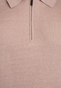 Gaiši brūns ribots džemperis ar īsu rāvējslēdzēju un salocītu apkakli, attēlots tuvplānā.