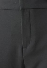 Black, stretchy fabric with a smooth texture; features a side seam pocket and clean edges for a tailored look.