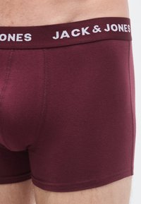 Vinröda boxershorts med en vit "JACK & JONES"-logotyp på den elastiska midjeresåren, med en slät textur och åtsittande design.