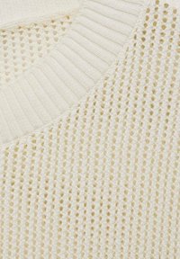 Pull tricoté crème avec une maille ajourée texturée, présentant un col côtelé et une finition douce. Accents de fil lisse visibles.