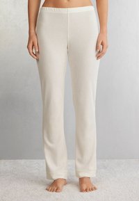 Witte geribde pyjamabroek met een brede elastische tailleband, rechte pijpen en strakke boorden bij de enkels, weergegeven op een lichte achtergrond.
