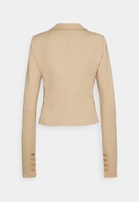 Beżowa dopasowana marynarka z wyciętym kołnierzem, długimi rękawami i pięcioma guzikami na mankietach. Gładki materiał z minimalnymi detalami szycia.