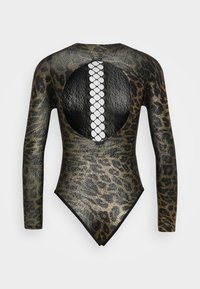 Långärmad bodysuit i guld och svart djurmönster, med ett stort cirkulärt utskärning och korsade detaljer på ryggen.