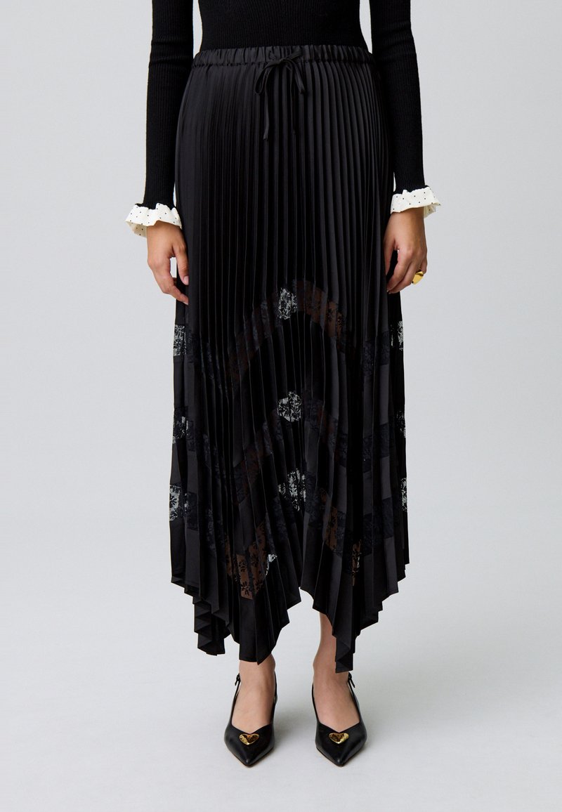 Jupe midi plissée noire avec une taille à cordon et des accents en dentelle florale, présentant une finition texturée et un ourlet asymétrique.