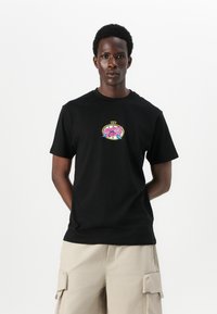 Svart bomull T-skjorte med et fargerikt grafisk logo på brystet, rund hals og korte ermer, sammen med beige cargo-shorts.
