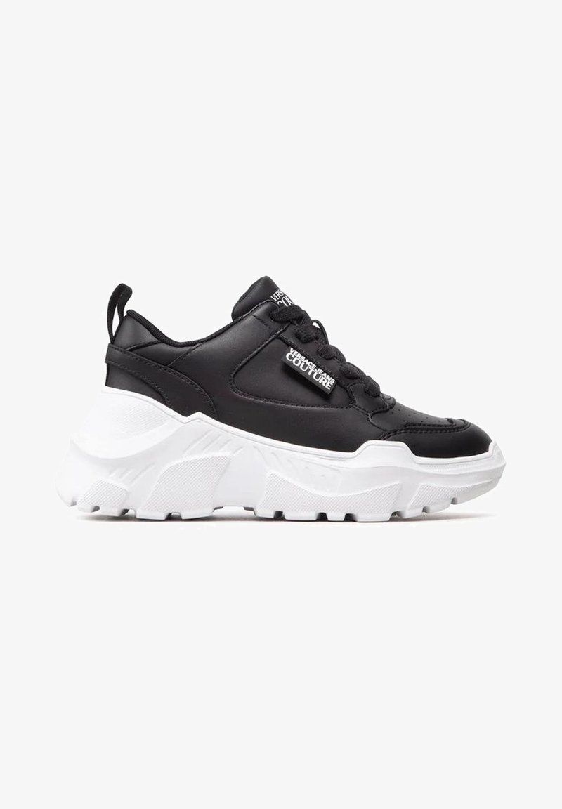Sneaker nere in pelle con suola bianca spessa, dotate di punta rotonda, collare imbottito e chiusura con lacci, marchiate "Versace Jeans Couture."