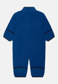 Macacão em fleece de um azul profundo, com um colarinho alto, mangas longas e punhos escuros em contraste. Textura suave com um design aconchegante.