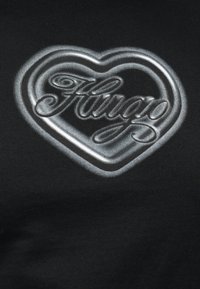 Μαύρο ύφασμα με ασημί μεταλλική καρδιά και τη λέξη "Fungao" γραμμένη μέσα στην καρδιά.