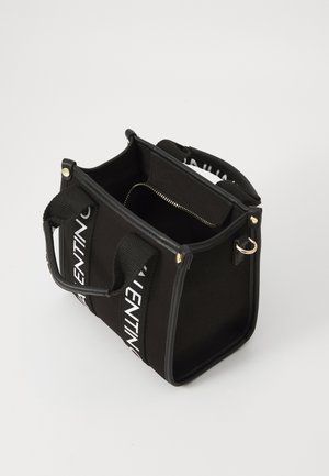 Sort lærredstaske med robuste håndtag og kontrastfulde hvide branded stropper. Indvendigt findes et rum med lynlås. Struktureret rektangulær form.