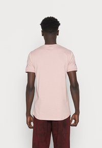 T-shirt med korte ærmer og rund hals i blød pink bomuld. Tætsiddende pasform med en buet kant, minimale sømdetaljer og ribbede manchetter.