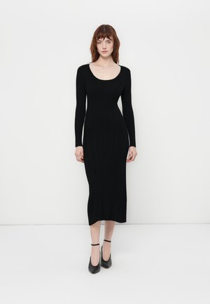 Black ribbed long-sleeve dress with a scoop neckline and slim fit, featuring a mid-calf length and subtle fringe detailing at the hem.