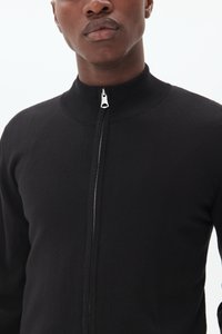 Black knit sweater with a high collar and silver zipper, featuring a smooth texture and fitted design.