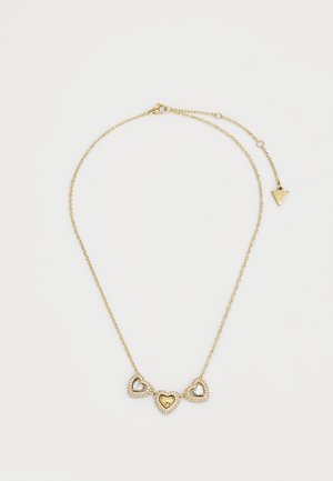 Collar de tono dorado que presenta tres colgantes en forma de corazón, dos adornados con cristales claros y uno con un corazón interior dorado. El diseño de la cadena es delicado.