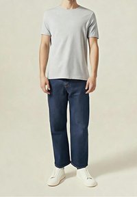 T-shirt en coton gris clair à manches courtes, associé à un jean bleu foncé à jambes droites et des chaussures blanches sans lacets. Design minimaliste, sans motifs.