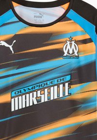 Melns sporta krekls ar ziliem un oranžiem diognāla svītrām, kurā ir "Olympique de Marseille" teksts un logo, izgatavots no sintētiskā materiāla.