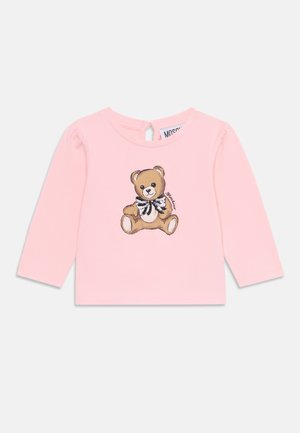 Camisa de manga larga rosa con cuello redondo, que presenta una gráfica de un oso de peluche con una pajarita en blanco y negro. Tejido suave con mangas fruncidas.