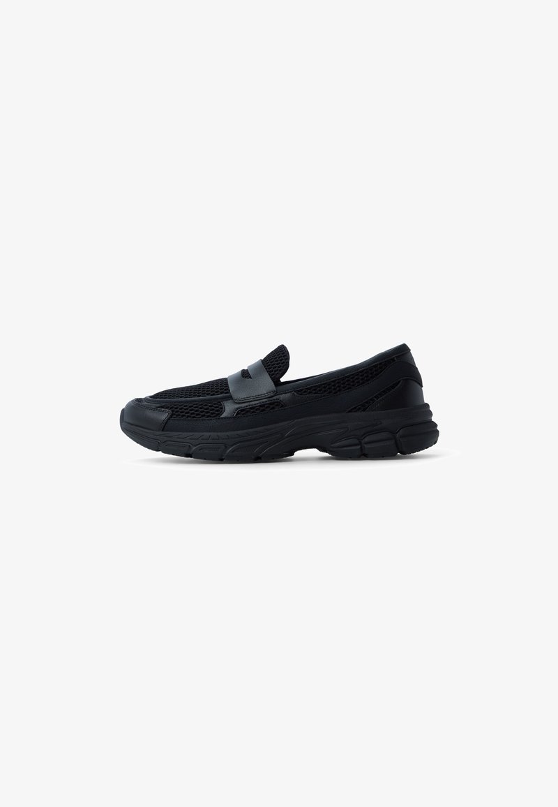 Black slip-on shoe featuring a mesh upper, synthetic accents, and a thick rubber sole with textured tread for grip.