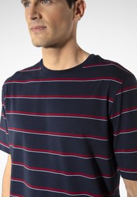 Navy blue short-sleeve t-shirt with horizontal red and white stripes, rounded neckline, soft cotton fabric, and relaxed fit.