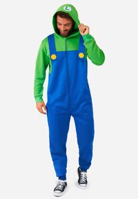Un monos azul y verde con capucha, con botones amarillos y una sección superior verde, hecho de una tela suave. El modelo lleva zapatillas negras.