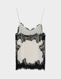 Κρεμ φόρεμα slip με λεπτές τιράντες και μαύρη φλοράλ δαντέλα κατά μήκος του ντεκολτέ, των πλευρών και του τελειώματος σε ανοιχτό φόντο.