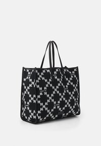 Grand sac fourre-tout en tissu noir présentant un motif géométrique blanc. Agrémenté de poignées noires et d'une forme structurée.