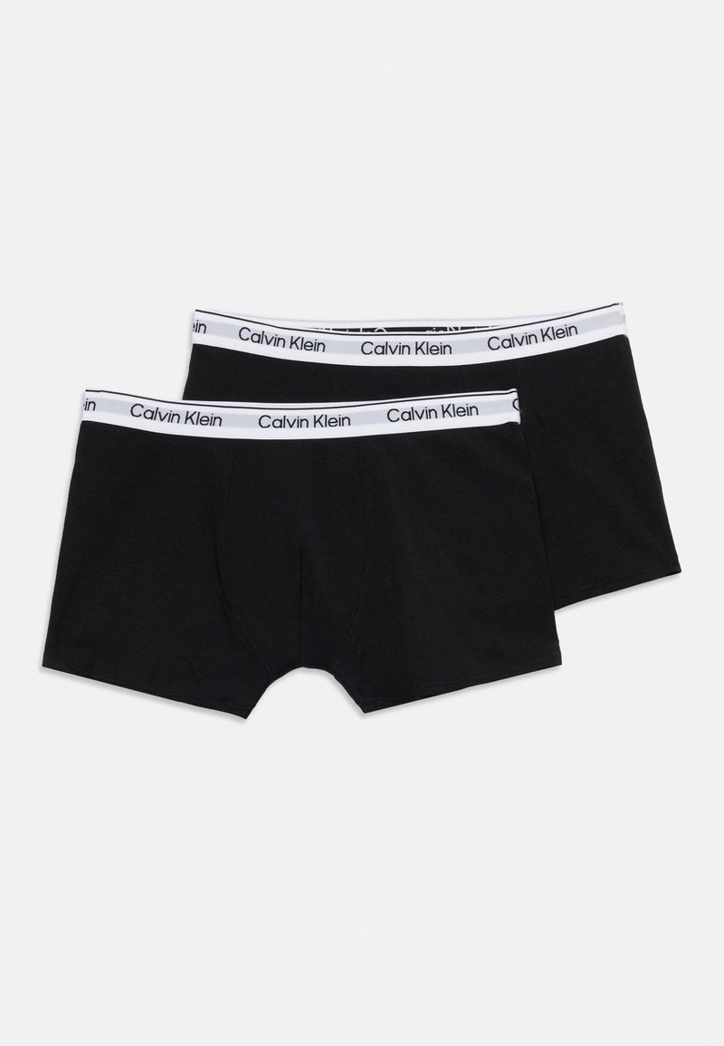 Δύο μαύρα ανδρικά εσώρουχα τύπου μπόξερ Calvin Klein με λευκές ελαστικές μέσες που φέρουν μαύρο εμπορικό κείμενο, τοποθετημένα επίπεδα σε λευκό φόντο.