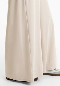 Helle beige weiter Hosren aus einem weichen, glatten Stoff, mit einer klaren Silhouette und dezenten Seitennähten.