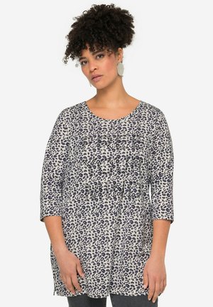 Leopardprint tunika i beige og marineblå med trekvartærmer og rund halsudskæring, prydet med teksten "FRIGØR DIN BEVIDSTHED" i krystalapplikationer.
