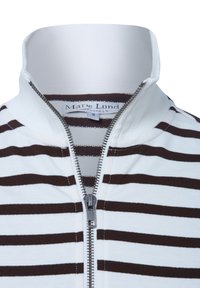 Biała i brązowa, paskowana kurtka z zamkiem błyskawicznym na wysoki kołnierz, z metalowym zamkiem i metką z napisem "Marie Lund, Kopenhaga." Rozmiar S.