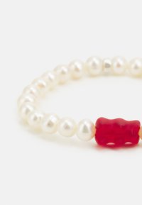 Braccialetto in perle con perle bianche tonde e un charm centrale a forma di orsetto gommoso rosso, con dettagli metallici per un tocco speciale.