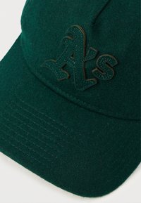 Cască de baseball verde din fetru cu logo-ul brodat "A's" în verde închis, suprafață texturată și detalii cusute pe margine.