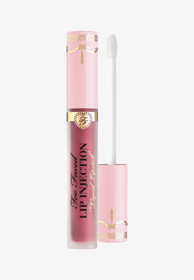 Flüssiger Lippenstift in einer Tube mit der Aufschrift "Too Faced Lip Injection", rosa Deckel und Applikator mit Flockspitze daneben, zeigt eine mauve Lippenfarbe.